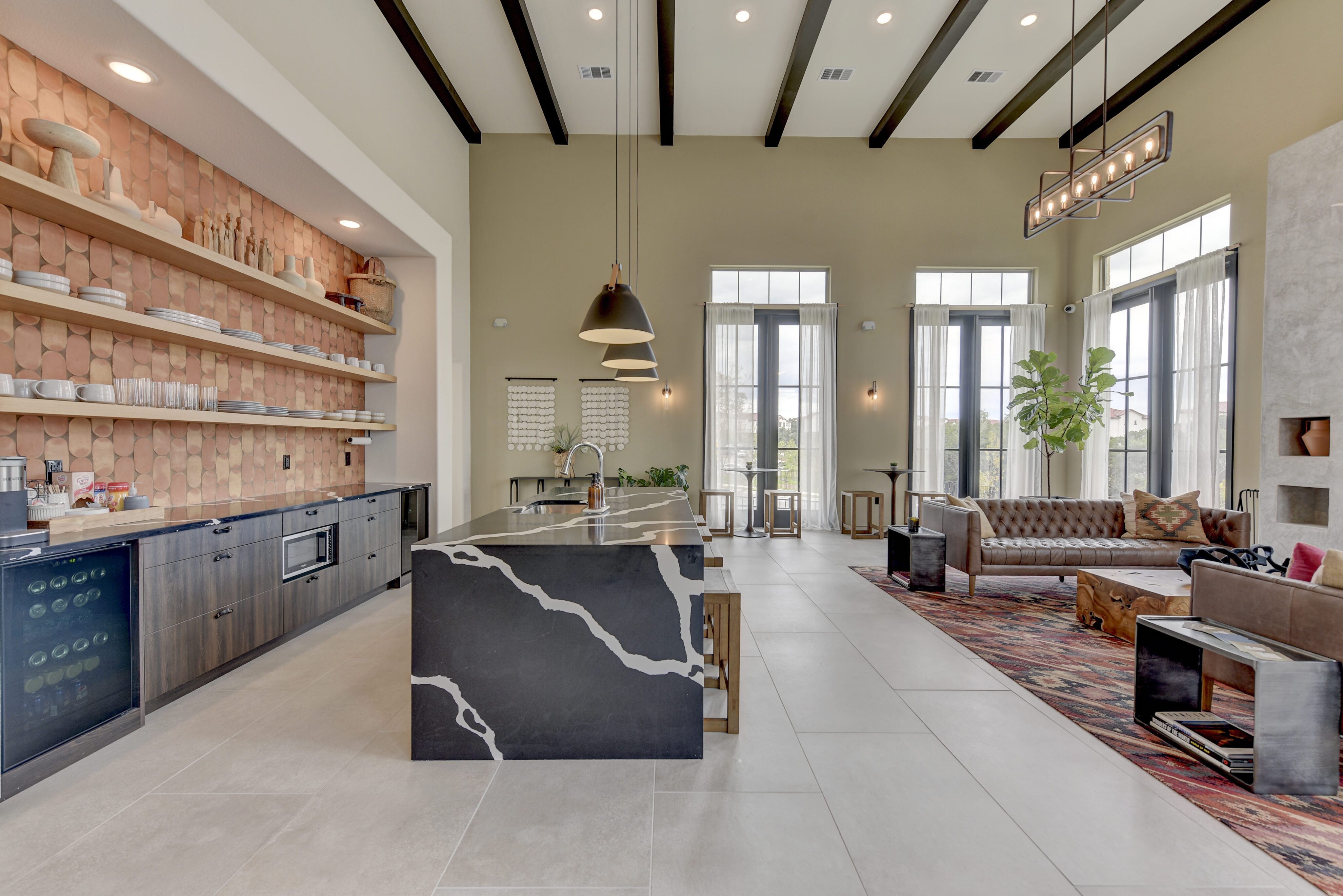 Modern open-concept kitchen and living area with high ceilings, black island, pendant lights, wooden shelves, and large windows.