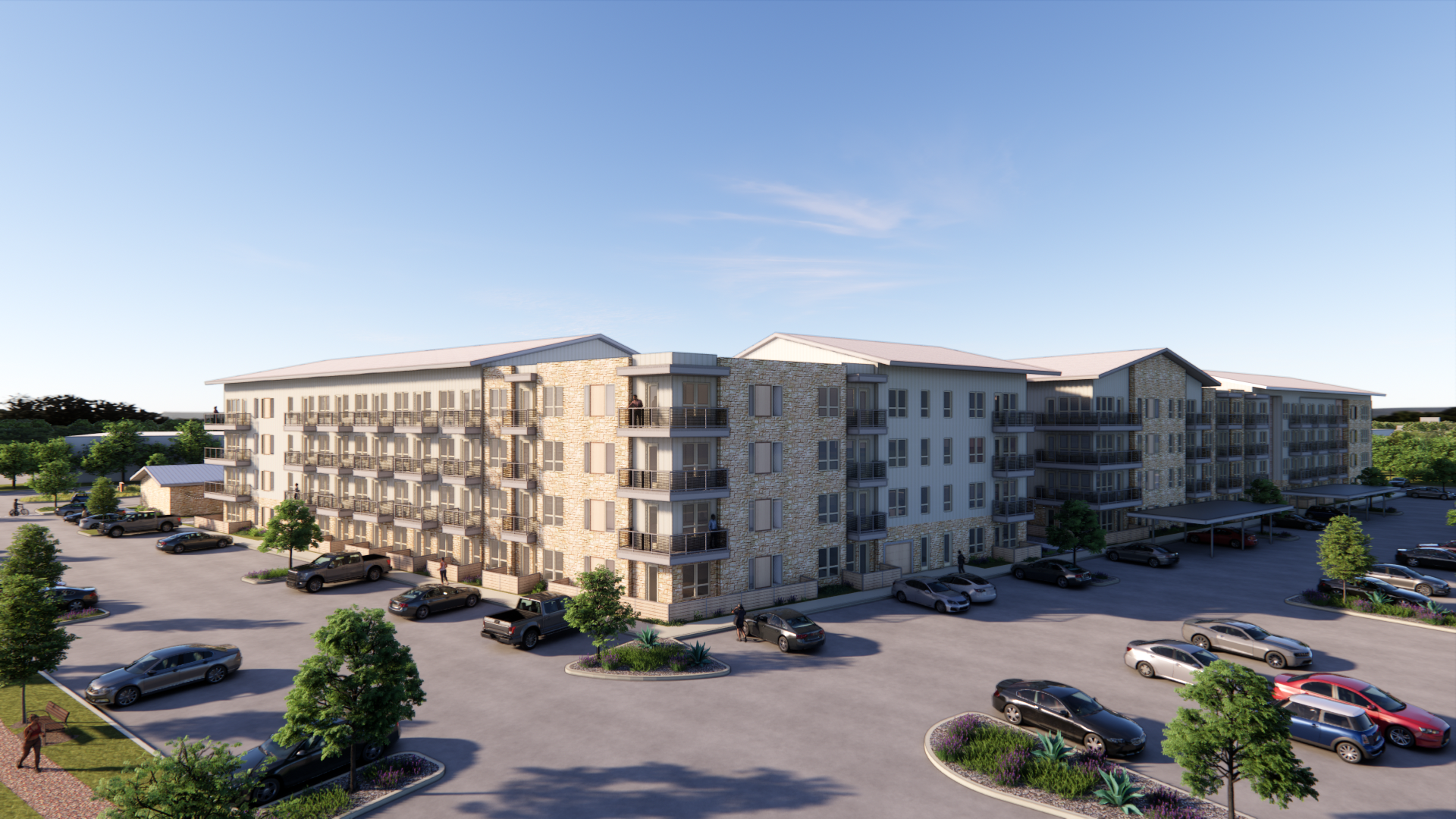 A four-story apartment building with balconies, surrounded by a large parking lot and trees, under a clear blue sky.